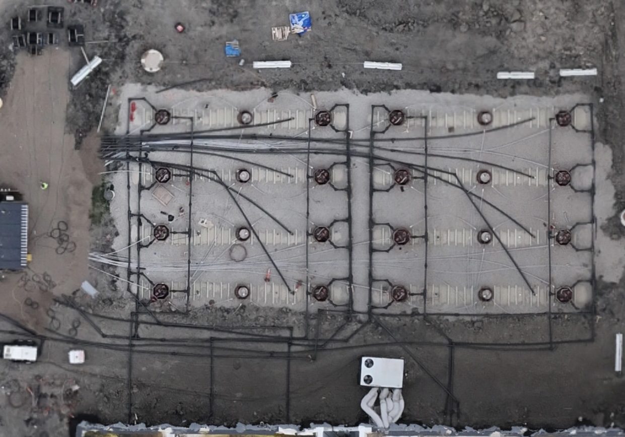 Aerial view of a data center generator fuel tank field with backfilled tanks and piping runs