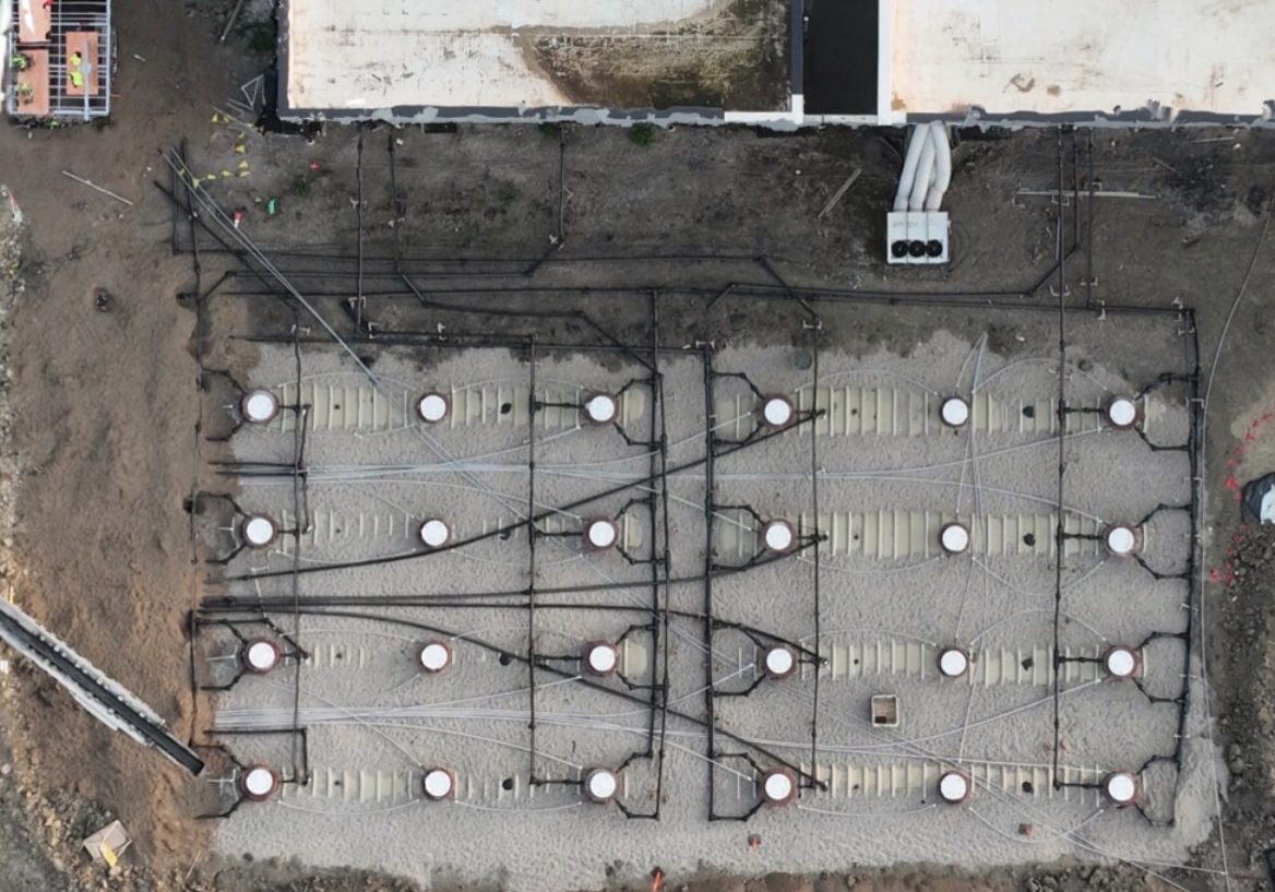 Aerial view of a data center fuel tank field beside the building, with tank risers and piping runs in place
