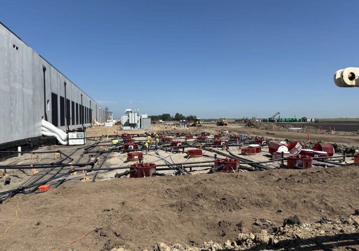 Wide view of fuel piping and tank sumps installed beside a data center building