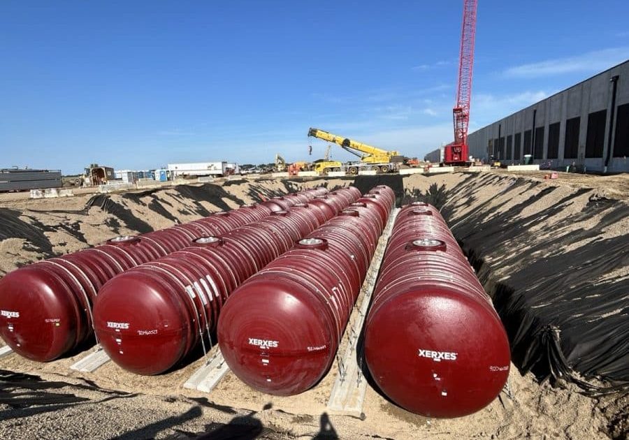 Red steel generator fuel storage tanks set in an excavation next to a data center